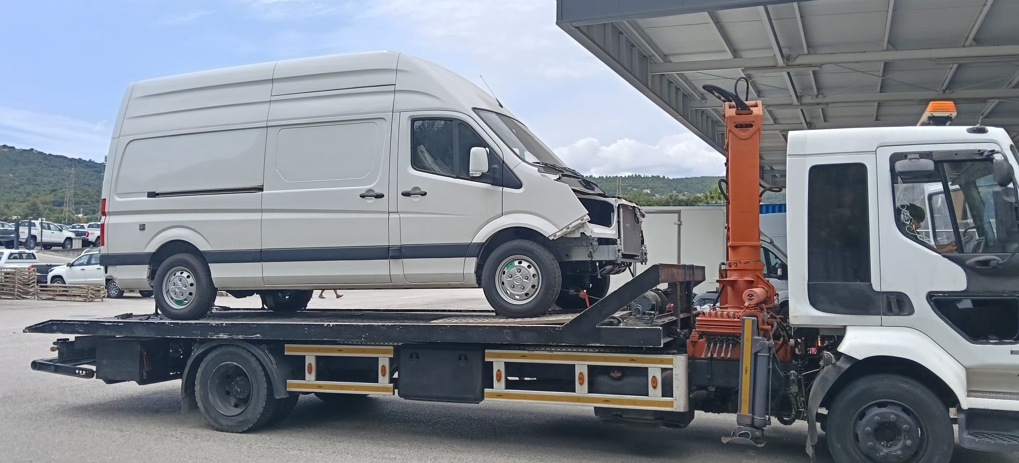 Caminhão de pronto socorro transportando uma van avariada